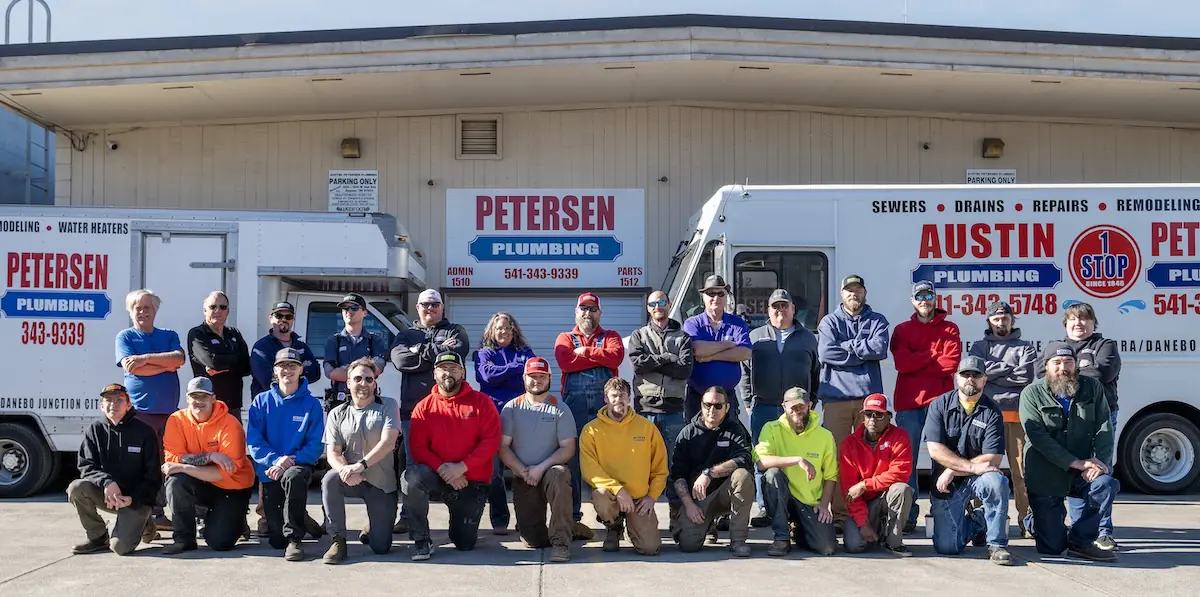 The Petersen Plumbing crew standing in front of the shop and two service trucks